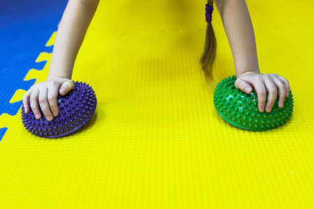 a little girl works on herself and stands in rack on spiked balls and does push-ups in a children's centerの写真素材