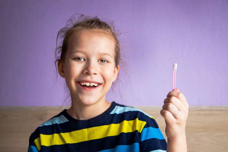 a child girl in a striped turtleneck demonstrates a cotton swab for ears as a symbol of purity.の写真素材