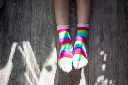 girl child shows two socks with rainbow colors put on her feet as a symbol or concept of lgbt...