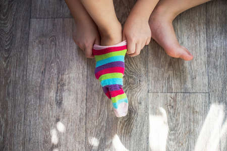 girl trying on one sock with rainbow colors as a symbol or concept of the lgbt community.の写真素材