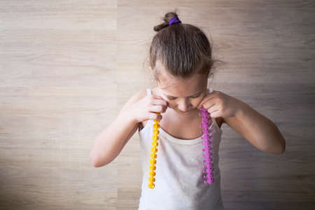 a girl plays with rubber tracks and presses them to her cheeks, the concept of an interesting game.の写真素材