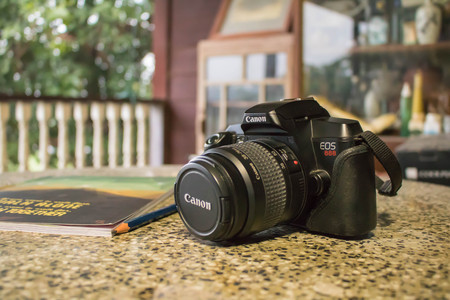 Old school Canon EOS 888 with notebook and pecil on a table