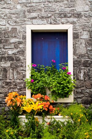 brick house with blue window and flowers decoration outsideの写真素材