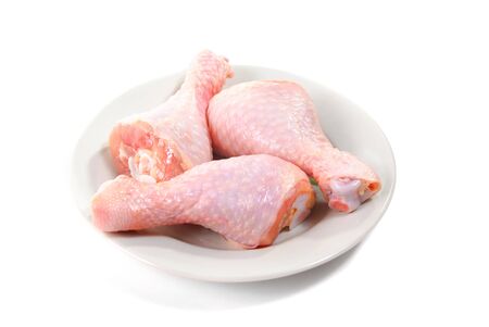 Three fresh raw chicken legs on plate, isolated on white backgroundの写真素材