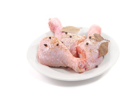 Three fresh raw chicken legs on plate with spices isolated on white backgroundの写真素材