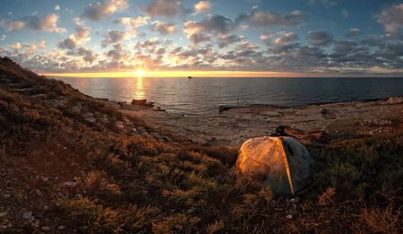 Beautiful seascape on sunrise with old boat on coast and clouds on backgroundの写真素材