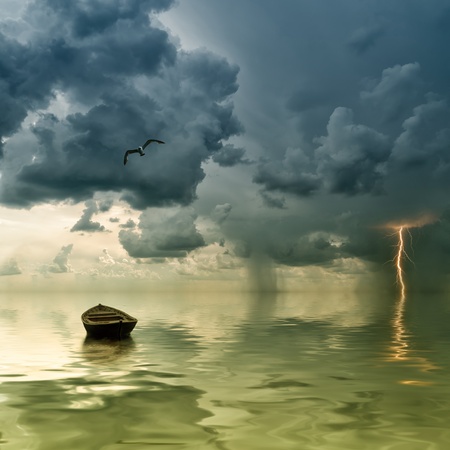 The lonely old boat at the ocean, comes nearer a thunder-storm with rain and lightning on backgroundの写真素材