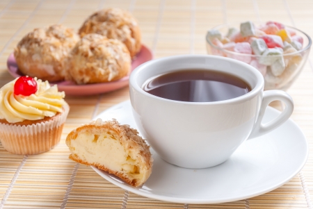 Close up green tea, fresh cherry muffin, colorful delight and eclairsの写真素材
