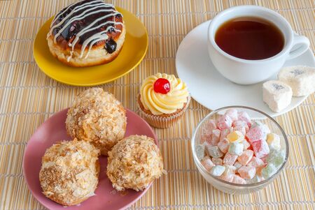 Tea, fresh cherry muffin, colorful delight, eclair and doughnutの写真素材