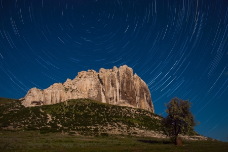 Night landscape with tree, mountaine and startrails in skyの写真素材