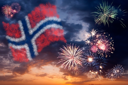 Beautiful colorful holiday fireworks with national flag of Norway, evening sky with majestic cloudsの写真素材