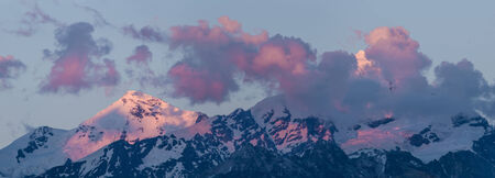 Big mountains in clouds on sunsetの写真素材