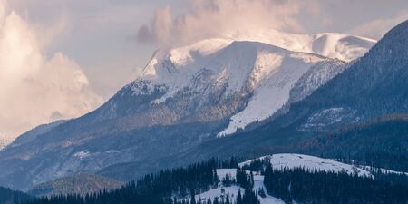 Panorama of high snowy mountains stretching into the sky with cloudsの写真素材