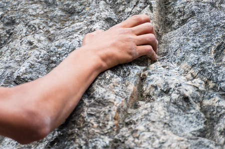 Climber's hand firmly holding a rock, extreme sport