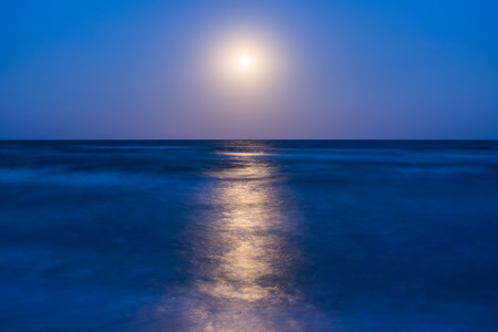 Night landscape with full moon and lunar path on sea, long exposureの写真素材