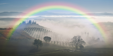 Agricultural landscape with rainbow and garden in fog, farmland, Tuscanyの写真素材