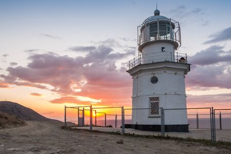 White lighthouse at cape, beautiful landscape with clouds on sunriseの写真素材
