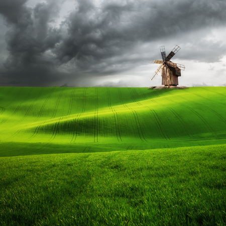 Vintage windmill on hill, green wheat field, agricultural landscapeの写真素材