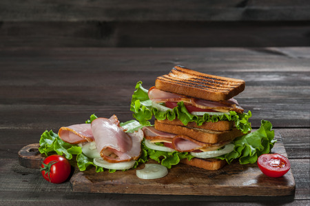Sandwiches with sausage and vegetables on dark wooden table. Selective focusの写真素材