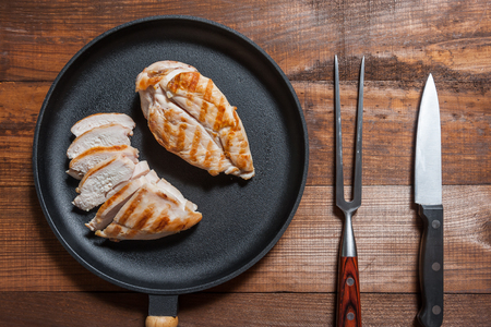 Grillad chiken fillet on pan, cooked meat. Wooden background, flat layの写真素材
