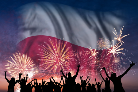 Happy people are looking holiday fireworks with flag of Poland in sky, independence dayの写真素材