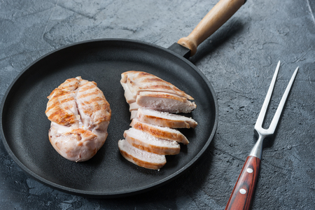 Grilled chicken fillet on frying pan. Raw vegetables in bowl, kitchen background. Selective focusの写真素材