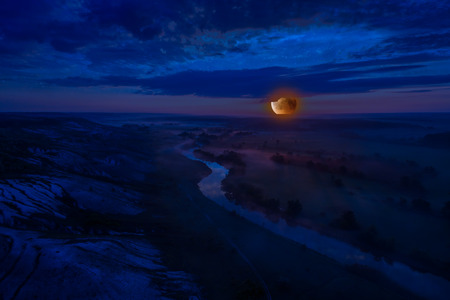 Landscape with bloody moon rise, river and night fog, make from drone, aerial viewの写真素材