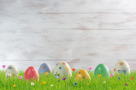 Easter holiday background with painted eggs and flowers in grass. Place for your text, copy spaceの写真素材