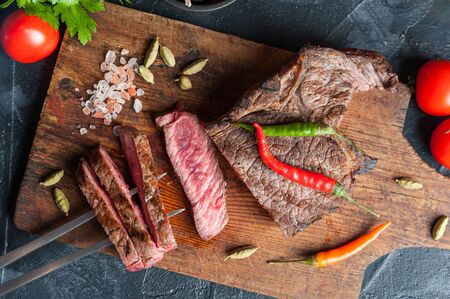 Grilled beef steak on wooden board. Hot fried meet with vegetables and spices. Selective focusの写真素材