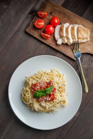 Italian spaghetti pasta with sauce and chicken, cheese parmesan and basil. Food background, flat layの写真素材
