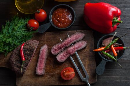 Grilled beef steak on wooden board. Hot fried meet with vegetables and spices. Selective focusの写真素材