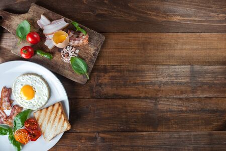 Fried eggs with bacon on breakfast on wooden rustic boards, food background, flat layの写真素材