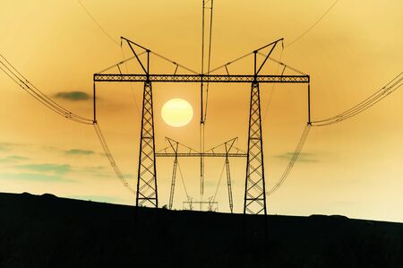 Industrial landscape with high-voltage power line, electric tower and rising sun. Retro stylization, vintage film filterの写真素材