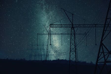 Industrial night landscape with high-voltage power line, electric tower and stars an sky. Retro stylization, vintage film filterの写真素材