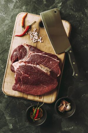 Beef steaks ready to cooking, culinary background. Fresh raw meat on wooden cutting board, flat lay. Retro stylization, vintage film filterの写真素材
