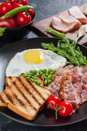 Fried eggs with bacon and vegetables, breakfast on wooden rustic boards, food backgroundの写真素材