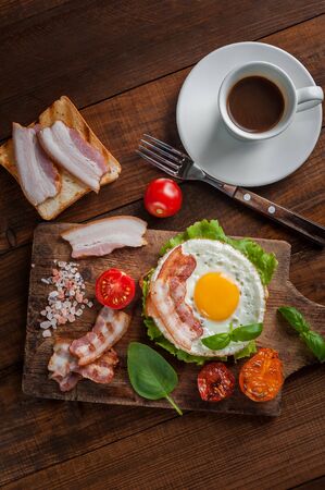 Fried eggs with bacon and vegetables, breakfast on wooden rustic boards, food backgroundの写真素材