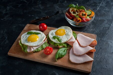 Fried eggs with bacon and vegetables, breakfast on wooden rustic boards, food backgroundの写真素材
