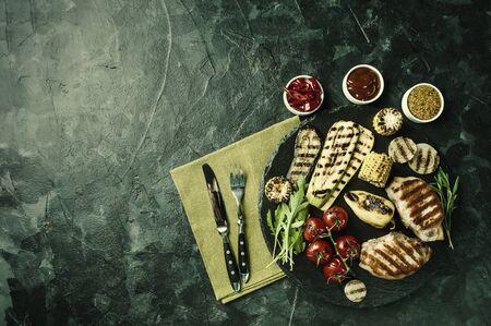 Fried pork fillet and grilled vegetables, delicious barbecue dinner, flat lay food background. Vintage stylization, retro film filterの写真素材