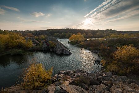 Fall landscape with river on sunset, colorful sky and bright autumn treesの写真素材