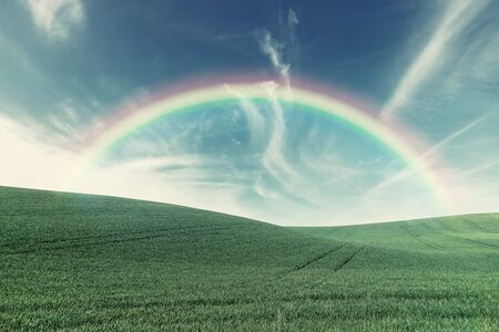 Beautiful agricaltural landscape with green field and rainbow over. Summer farmland. Vintave stylization, retro film filterの写真素材