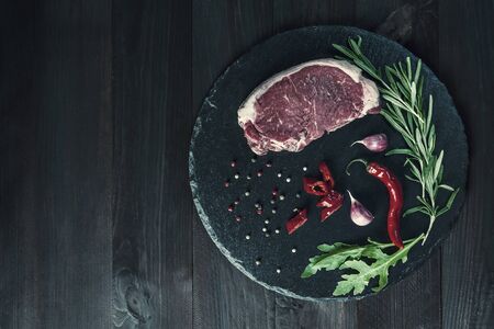 Beef steaks ready to cooking, culinary background. Fresh raw meat on cutting board with rosemary, flat lay. Vintage stylization, retro film filterの写真素材