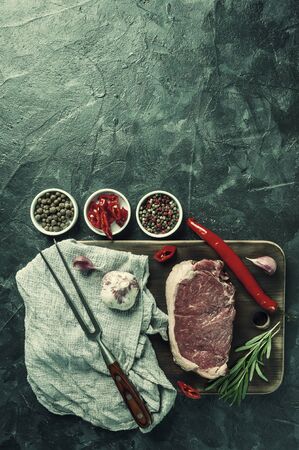 Beef steaks ready to cooking, culinary background. Fresh raw meat on wooden cutting board with rosemary, flat lay. Vintage stylization, retro film filterの写真素材