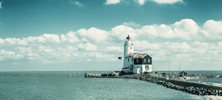 Landscape with lighthouse on seashore, dramatic seascape, panorama. Vintage stylization, retro film filterの写真素材