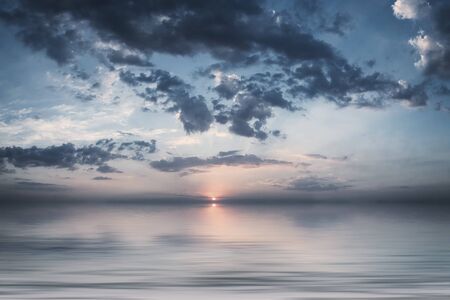 Nature background with sunset or sunrise above sea, beautiful couds in sky, seascape. Vintage stylization, retro film filterの写真素材