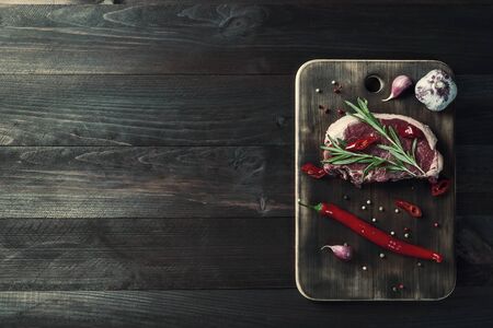 Beef steaks ready to cooking, culinary background. Fresh raw meat on wooden cutting board with rosemary, flat lay. Vintage stylization, retro film filterの写真素材