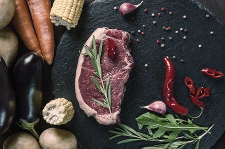 Steak ribyey ready to cooking, culinary background. Fresh raw beef meat on cutting board with rosemary, flat lay. Vintage stylization, retro film filterの写真素材