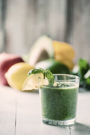Green smoothie from different vegetables and fruit on wooden table. Healthy eating for long life. Vintage stylization, retro film filterの写真素材