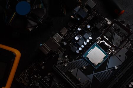 Multi core CPU installation on computer motherbord. PC assembly or upgrade on modern chipset. Electronic concept with processor, low lightsの写真素材