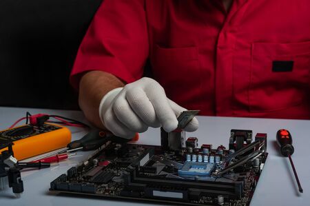 Multi core CPU installation on computer motherbord. PC assembly or upgrade on modern chipset. Electronic concept with processor, low lightsの写真素材